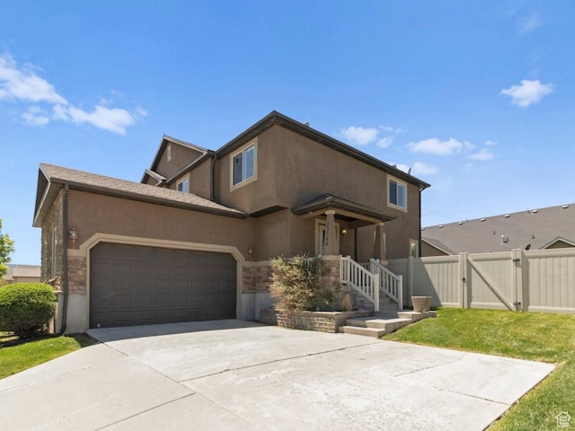 view of front of home featuring a gate, an attached garage, driveway, stucco siding, and stone siding
