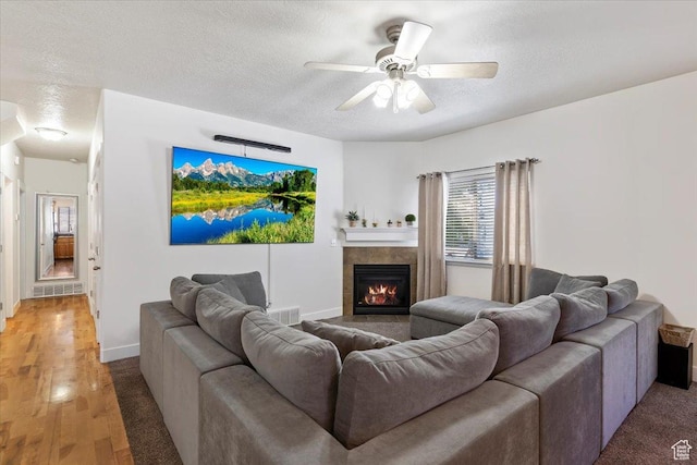 2099 W 700 S, Syracuse, UT 84075 - living room featuring a textured ceiling, ceiling fan, baseboards, a tile fireplace, and light colored carpet