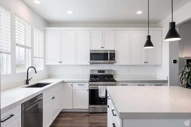 kitchen featuring stainless steel appliances, a sink, recessed lighting, white cabinets, and dark wood-style flooring