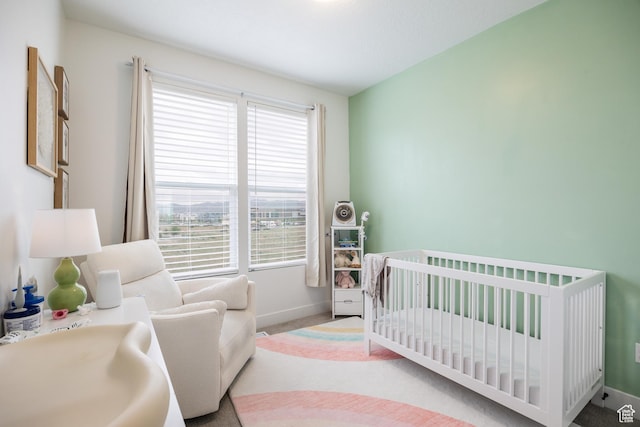 bedroom with a crib, baseboards, and carpet flooring