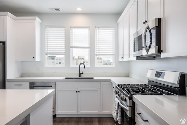 kitchen with stainless steel appliances, a sink, plenty of natural light, white cabinets, and recessed lighting