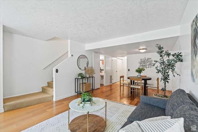 living room featuring wood finished floors, stairway, a textured ceiling, and baseboards