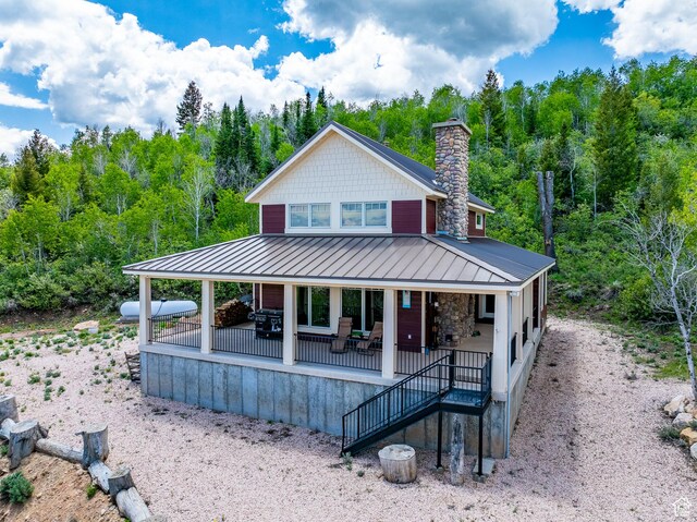 3431 S Panorama Dr, Garden City, UT 84028 - farmhouse inspired home featuring a standing seam roof, a chimney, a view of trees, and metal roof