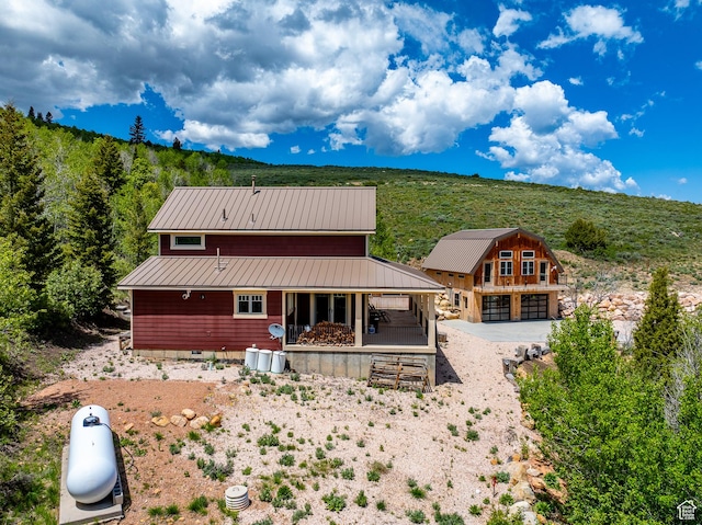 3431 S Panorama Dr, Garden City, UT 84028 - back of house with metal roof, an outdoor structure, gravel driveway, crawl space, and a forest view