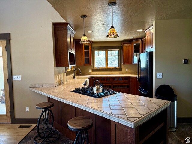 3431 S Panorama Dr, Garden City, UT 84028 - kitchen with black appliances, a peninsula, glass insert cabinets, baseboards, and a sink