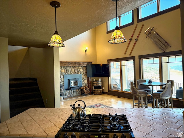3431 S Panorama Dr, Garden City, UT 84028 - kitchen with tile countertops, a textured ceiling, high vaulted ceiling, a fireplace, and stovetop