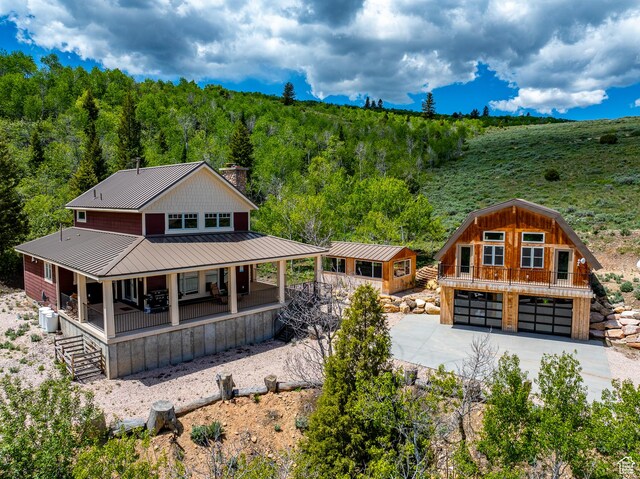 3431 S Panorama Dr, Garden City, UT 84028 - view of front of home with covered porch, a chimney, a view of trees, driveway, and metal roof