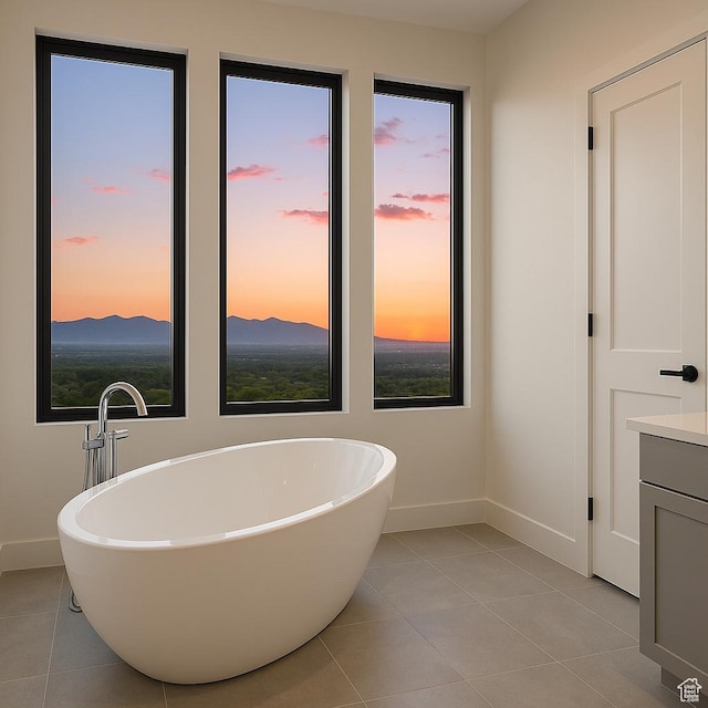 full bath with baseboards, tile patterned floors, and a soaking tub