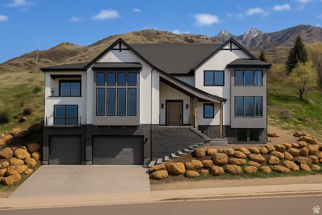 view of front facade featuring a mountain view, stucco siding, an attached garage, and driveway