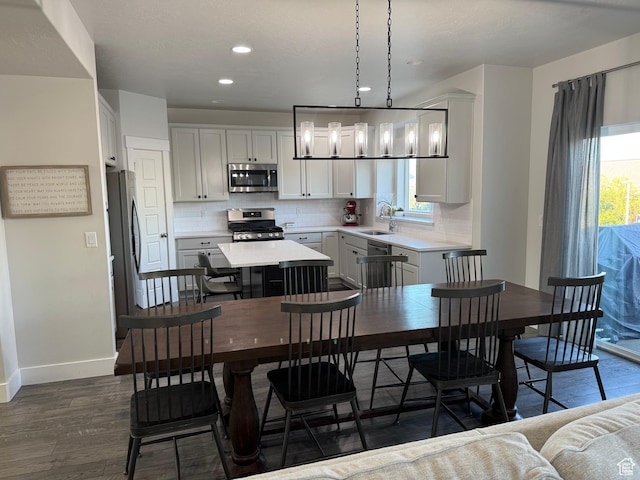 kitchen featuring appliances with stainless steel finishes, a sink, dark wood-style floors, backsplash, and healthy amount of natural light