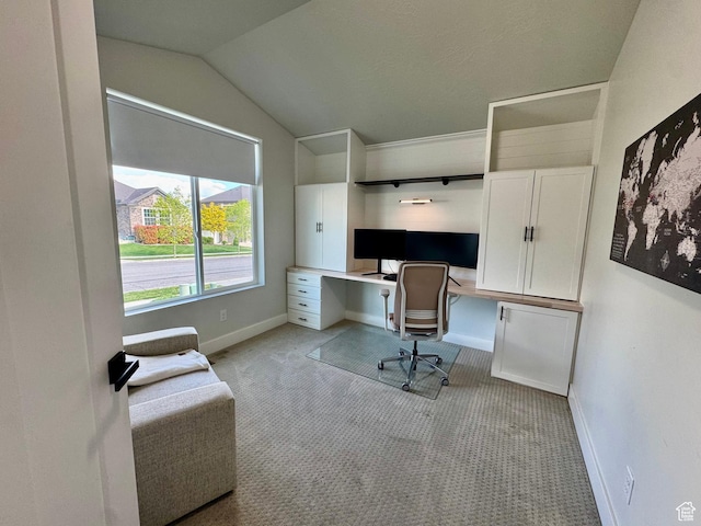 office area featuring light carpet, built in study area, baseboards, and lofted ceiling