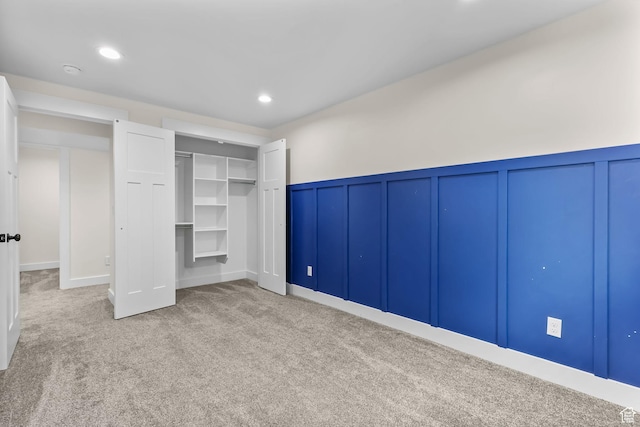 unfurnished bedroom with a decorative wall, carpet, a wainscoted wall, recessed lighting, and a closet