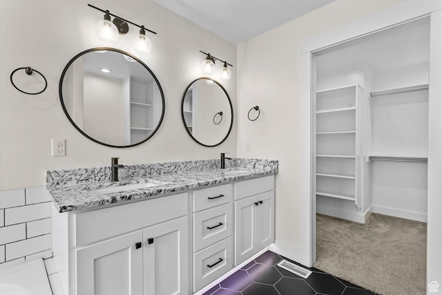 bathroom with a spacious closet, double vanity, and tile patterned floors