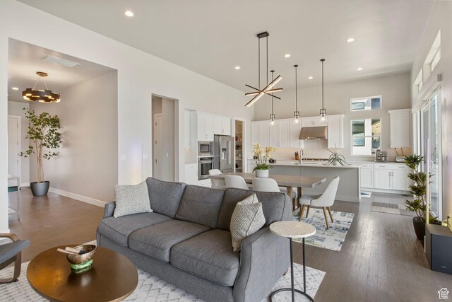 living room featuring a chandelier, dark wood-style floors, baseboards, recessed lighting, and a high ceiling
