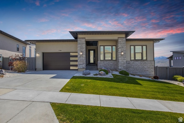 view of front of home featuring an attached garage, concrete driveway, stone siding, and stucco siding