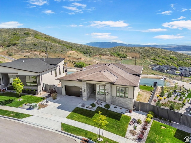 view of front facade with an attached garage, driveway, a mountain view, and stone siding