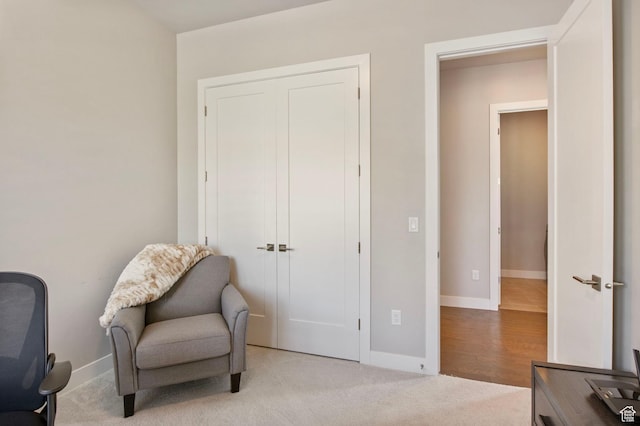 sitting room with baseboards and light colored carpet