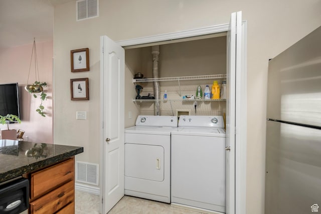 laundry area with washer and dryer and light tile patterned floors