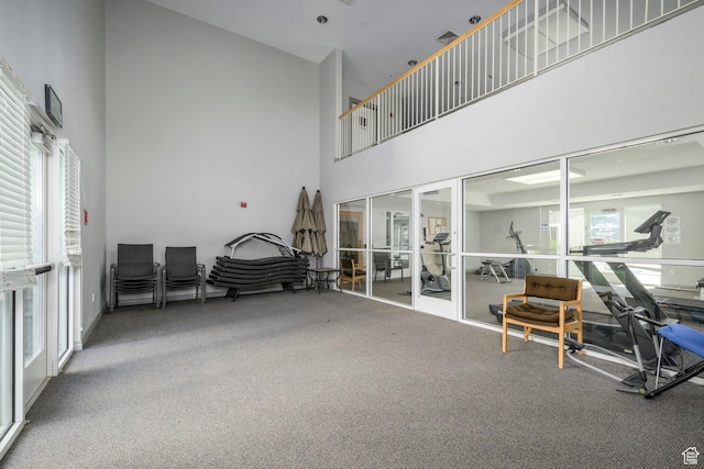 carpeted living room with a towering ceiling and french doors