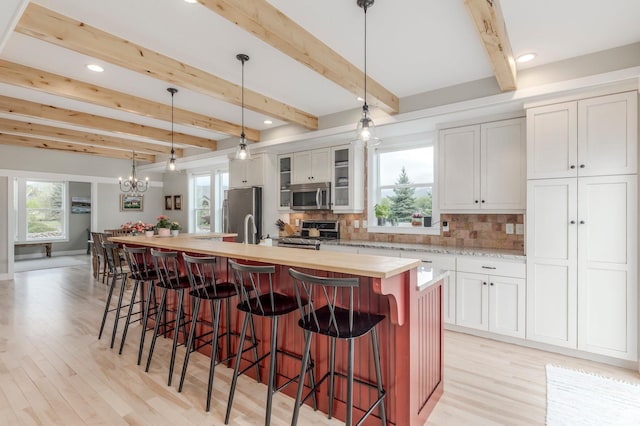 1920 S Wall St, Heber City, UT 84032 - kitchen with stainless steel appliances, a spacious island, light wood-type flooring, decorative backsplash, and a chandelier