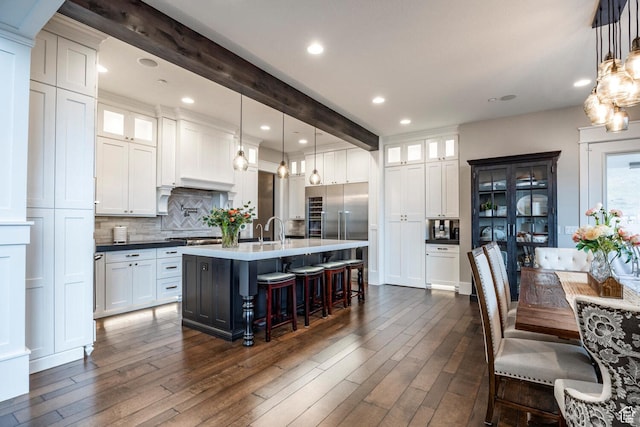 5314 W Rolling Brook Dr, Herriman, UT 84096 - kitchen with tasteful backsplash, dark wood-style flooring, a center island with sink, glass insert cabinets, and beamed ceiling