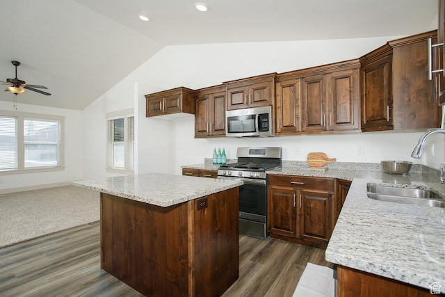 kitchen with stainless steel appliances, a sink, vaulted ceiling, dark wood-type flooring, and ceiling fan