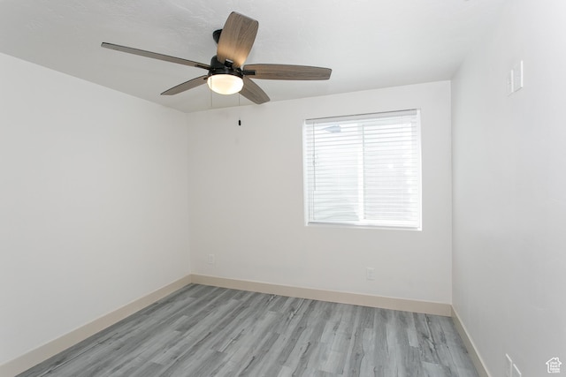 spare room featuring light wood-style flooring, a ceiling fan, and baseboards