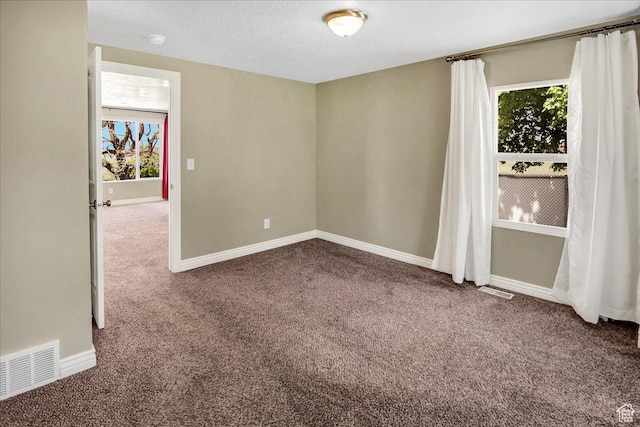 carpeted spare room featuring baseboards and a smoke detector