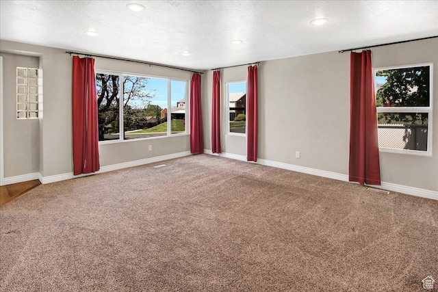 spare room with carpet flooring, baseboards, recessed lighting, and a textured ceiling