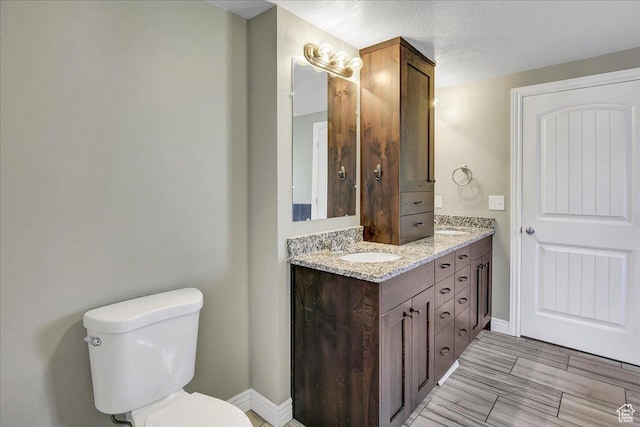 full bath featuring toilet, double vanity, and baseboards