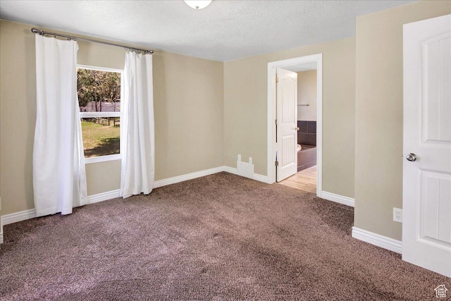 carpeted spare room featuring baseboards and a textured ceiling