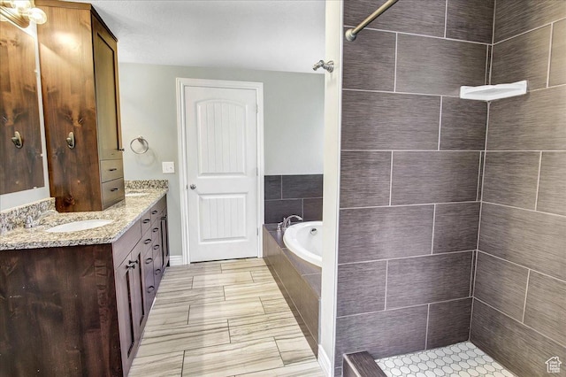 full bathroom featuring vanity, a garden tub, and a tile shower