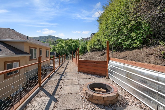 14038 S New Saddle Rd, Draper, UT 84020 - view of property exterior featuring fence, an outdoor fire pit, stucco siding, roof with shingles, and a mountain view