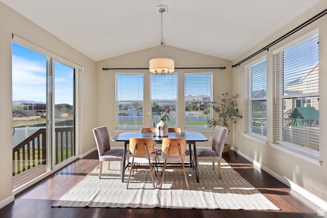 dining room featuring plenty of natural light, lofted ceiling, a chandelier, dark wood finished floors, and baseboards