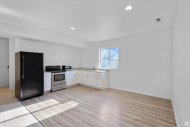 kitchen with appliances with stainless steel finishes, a sink, white cabinets, light countertops, and light wood-style flooring