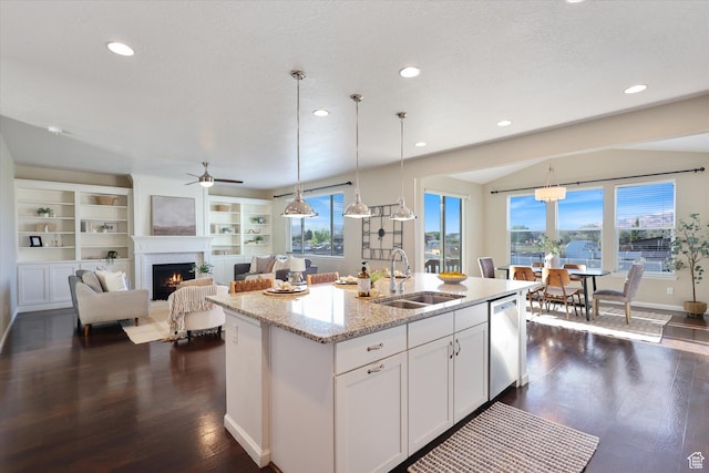 kitchen with a sink, stainless steel dishwasher, a lit fireplace, recessed lighting, and a center island with sink