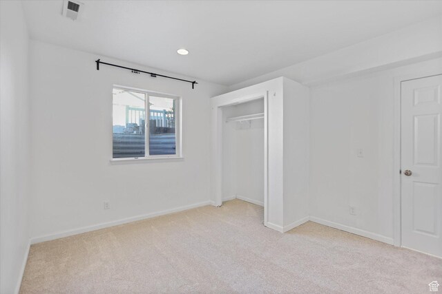 unfurnished bedroom featuring light colored carpet, baseboards, a closet, and recessed lighting