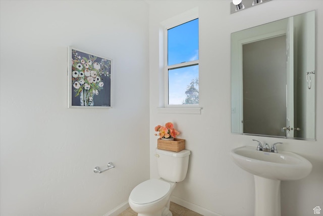 bathroom featuring baseboards, toilet, and a sink