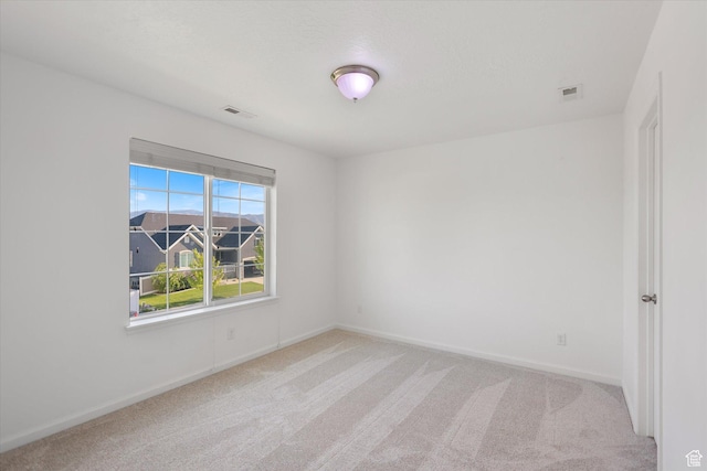 unfurnished room featuring light carpet and baseboards