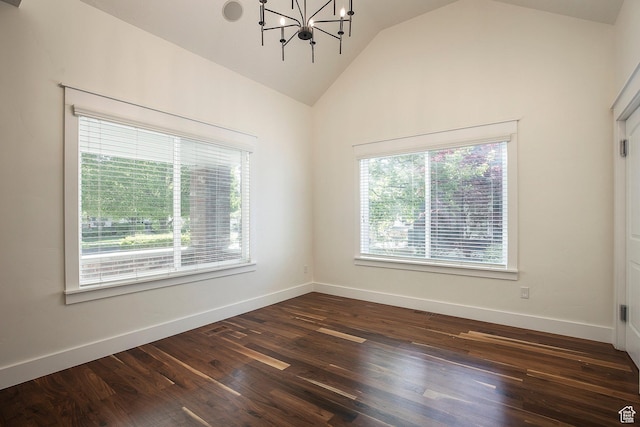 spare room with vaulted ceiling, dark wood-style floors, a chandelier, and baseboards