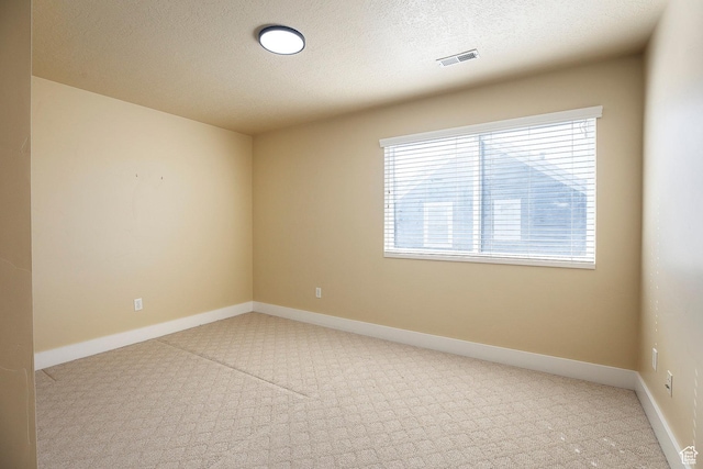 empty room with carpet, a textured ceiling, and baseboards
