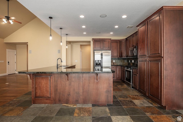 kitchen with stainless steel appliances, a kitchen bar, stone tile floors, recessed lighting, and a textured ceiling