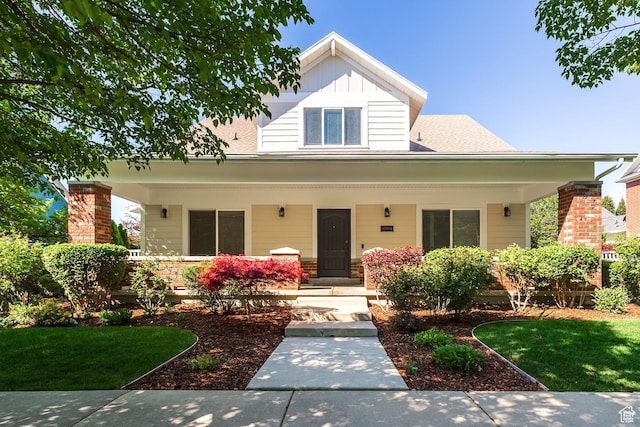 view of front of property featuring covered porch, board and batten siding, and a front yard