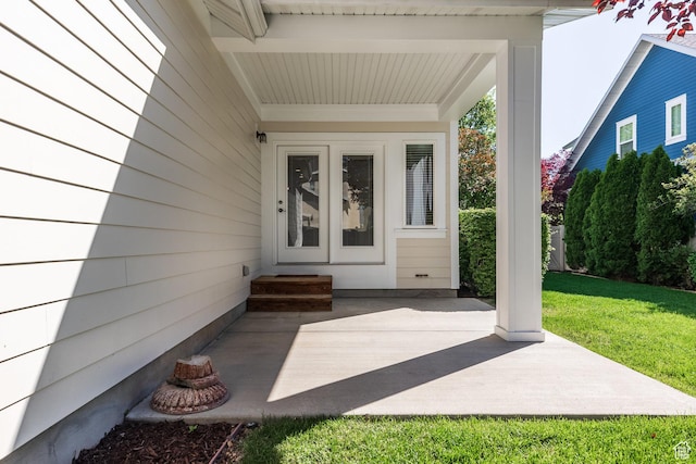 view of exterior entry featuring a patio and a yard