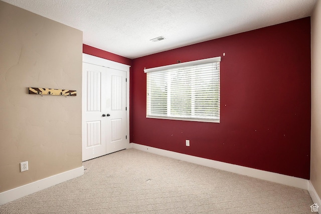 empty room featuring carpet, a textured ceiling, and baseboards