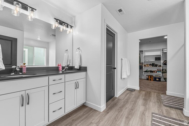 2607 N Mclaws Ave, Layton, UT 84040 - bathroom with wood finished floors, double vanity, a walk in closet, and baseboards