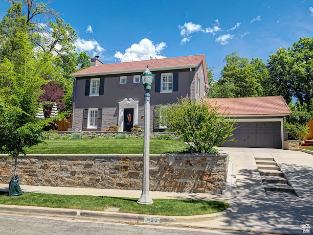 1133 S 1400 E, Salt Lake City, UT 84105 - colonial house featuring concrete driveway, an attached garage, a chimney, a front lawn, and stone siding