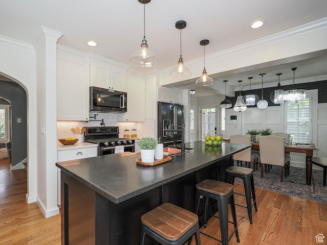 1133 S 1400 E, Salt Lake City, UT 84105 - kitchen with appliances with stainless steel finishes, arched walkways, white cabinets, tasteful backsplash, and light wood finished floors