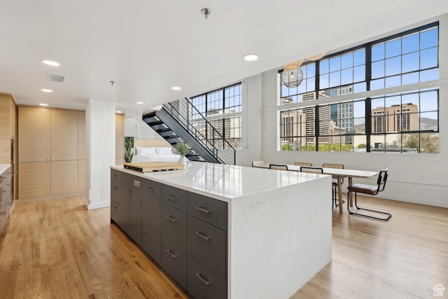 kitchen featuring modern cabinets, light wood-style floors, a kitchen island, recessed lighting, and dark cabinets