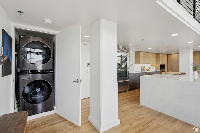laundry room with stacked washer / dryer, light wood-style flooring, and recessed lighting